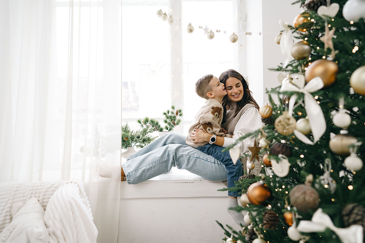 madre e hijo en una ventana y árbol de Navidad